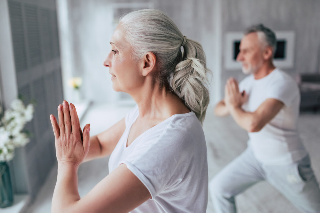 Senior couple at home Senior couple is doing fitness training at home. Doing yoga together. Healthy lifestyle concept.